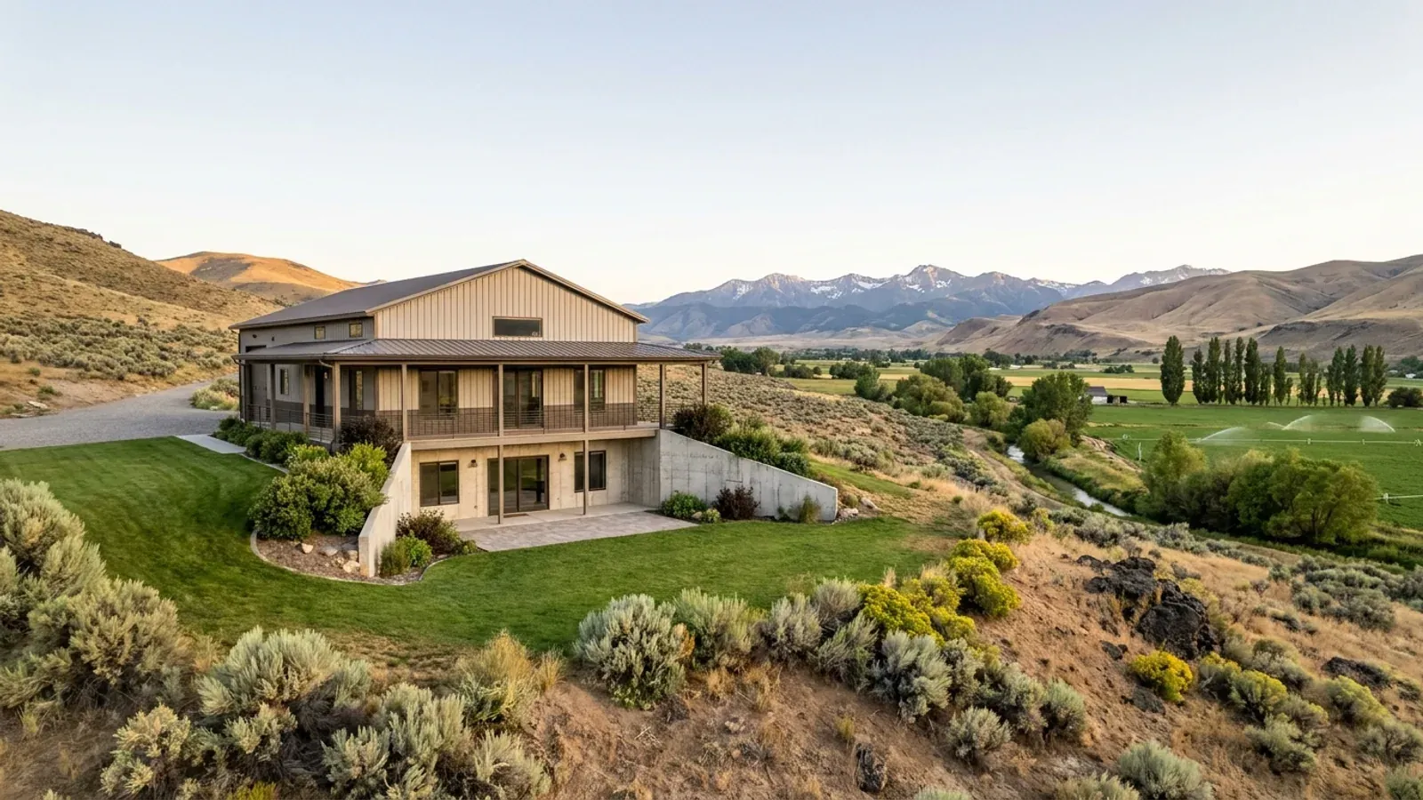 A barndominium with a walkout basement built into a sloping foothill lot, the lower level opening onto a patio at grade.