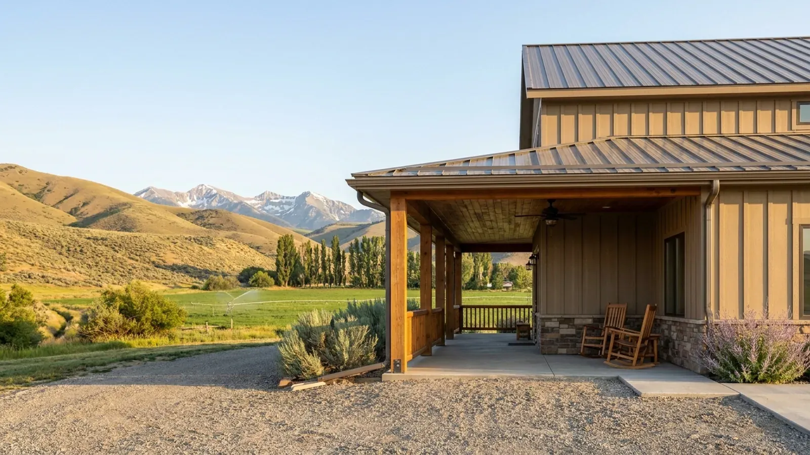 A barndominium exterior showing a deep wrap-around covered porch with posts and railing along two sides of the building.